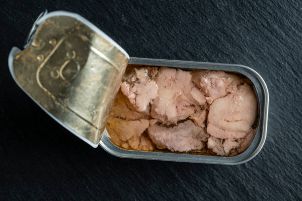 istock Open tin can with cod liver on black background, closeup, top view 1472791502