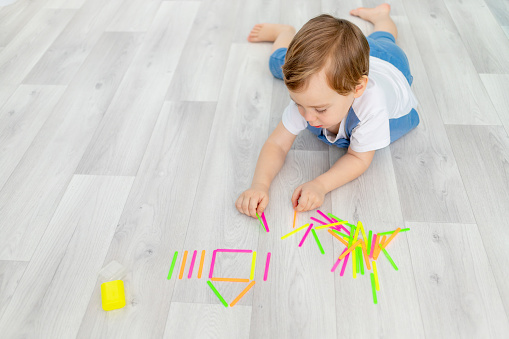 baby playing with counting sticks at home, cute boy building a house