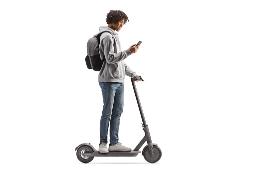 African american gen z male riding an electirc scooter and using a smartphone isolated on white background