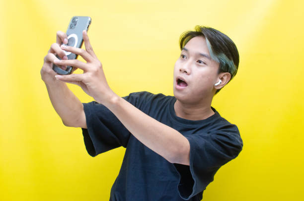 istock Asian man enjoying music using wireless earphone while holding phone 1472801062