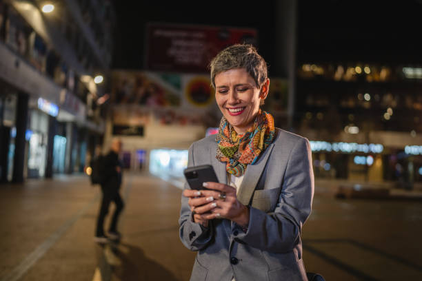 istock Senior woman use mobile phone send sms text message in city at night 1472801155