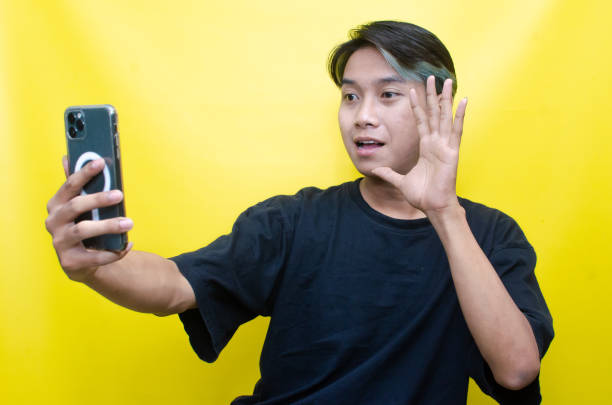 istock Asian man enjoying music using wireless earphone while holding phone 1472804093