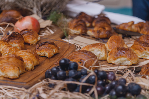 Rows of fresh baked French croissants with grape and pomegranate fruits decorated ready to be sold in Paris, France