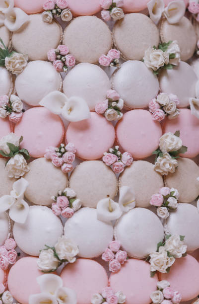 French patisserie baking flower decorated fresh pink and white coloured macaroons on a glass and tree stand