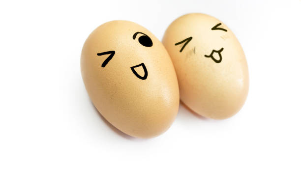 istock Two yellow eggs with painted emoticons on a white background. Eggs with a face. Smiley on eggs. Eggs with smiles and eyes on white. 1472804664