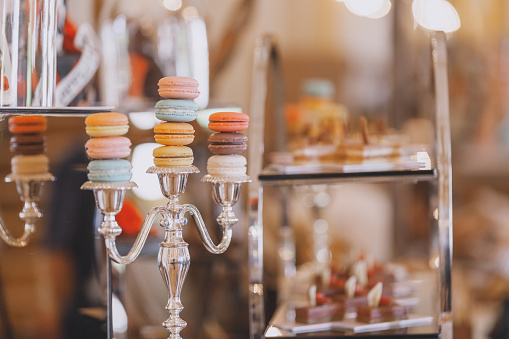 Different colors and kinds of French cookie macarons on a chandelier service stand at a celebration buffet