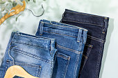 Different kind of jeans with wooden hangers on blue background