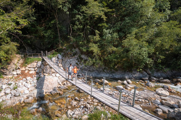 istock Couple crossing the suspension bridge over a mountain river 1472807746
