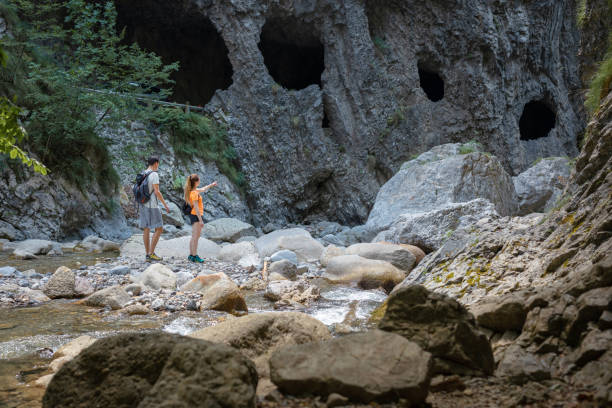 istock Hiker couple jumping on the rocks while crossing mountain river 1472807985