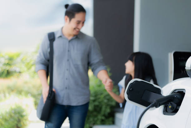 istock Focus EV car recharging battery at home with progressive people in background. 1472809648