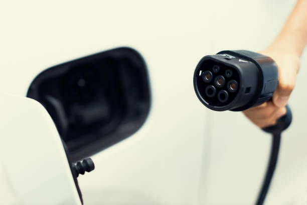 istock Progressive idea of focus hand pointing charging plug at camera, blur background 1472810419