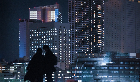 Silhouette of a loving couple kissing against the backdrop of numerous high-rise buildings in Yokohama ,Japan at night