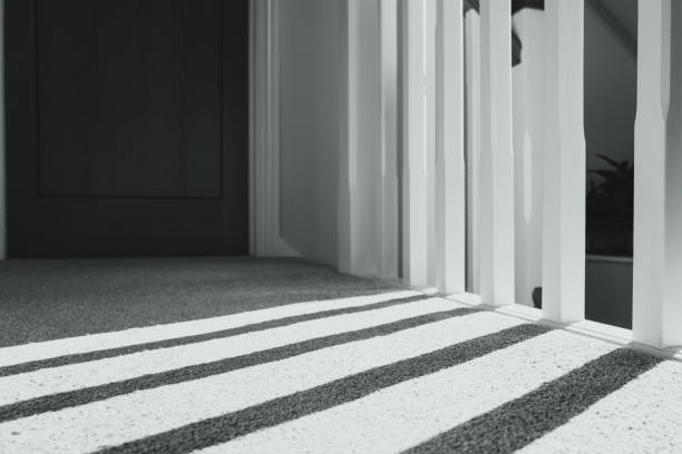 Abstract, monochrome view of dark shadows produced by skylight windows letting in sunlight to a modern, first floor landing.