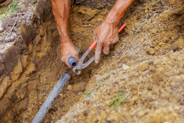 istock Installing an underground sprinkler system for watering the yard garden, a man works with pipes in the ground while installing the system 1472815405