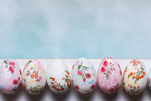 Easter eggs decorated with decoupage technique on a white board on a light blue background with copy space