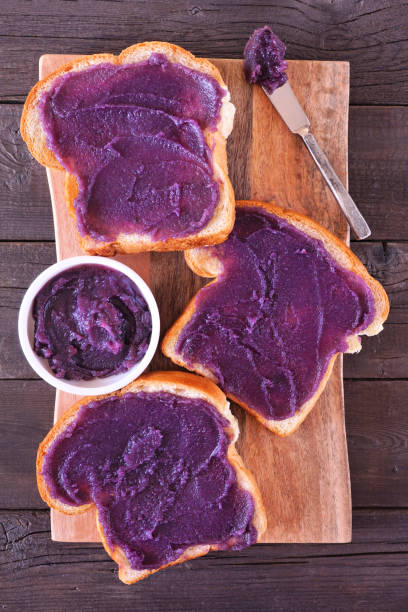 Toast with ube halaya, purple yam spread on a wood serving platter Toast with ube halaya jam. Sweet, trendy, purple yam spread. Top down view on a wood serving platter. ube purple yam stock pictures, royalty-free photos & images