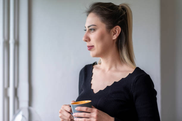 istock Beautiful woman looking out the window 1472820560