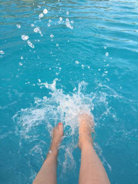 Women’s Feet splashing in blue pool water