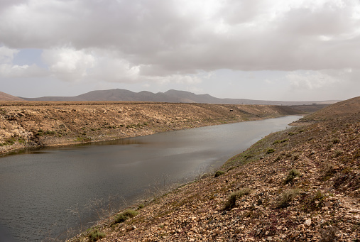 The largest reservoir of the fresh water on the islands, located in a valley. The best birding area. Cloudy sky in the winter. Embalse de los Molinos, Fuerteventura, Canary Islands.