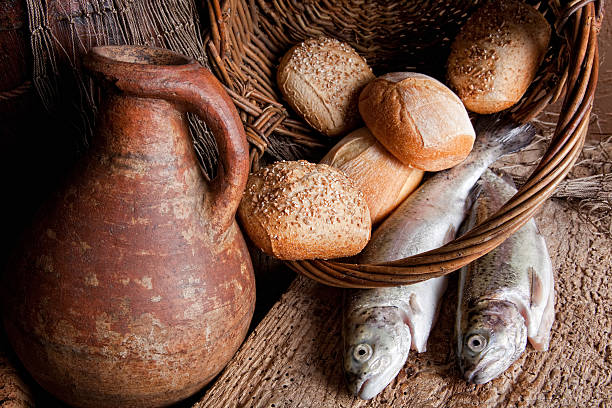 Holy multiplication Wine, loaves of bread and fresh fish in an old basket loaf of bread stock pictures, royalty-free photos & images