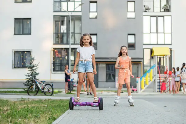 Photo of Happy children riding on hoverboards or gyro scooters outdoors in summer. Roller skating.