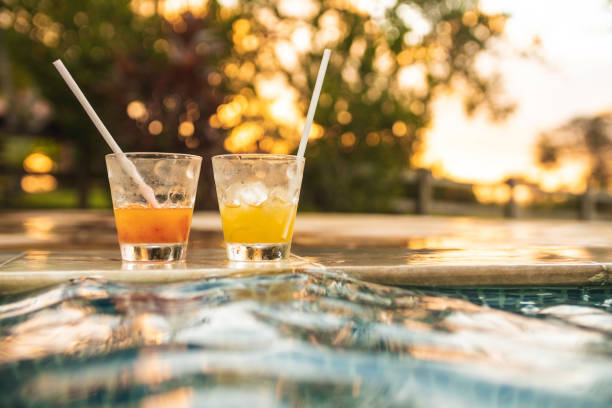 Glasses of drinks by the pool Glasses of drinks by the pool during sunset golden hour drink stock pictures, royalty-free photos & images