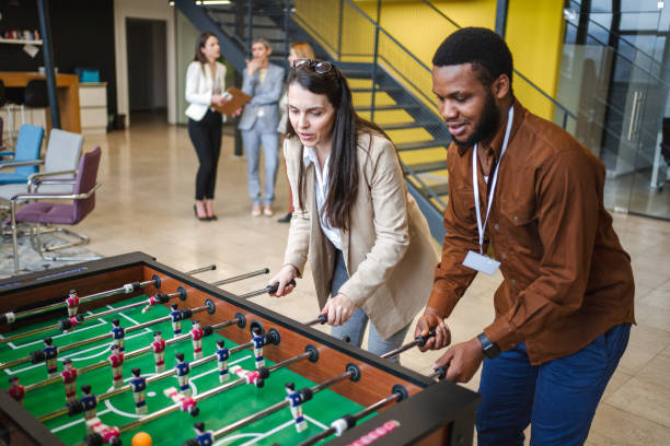 istock Two multiracial business colleagues having fun while playing foosball on a break from work 1472828814