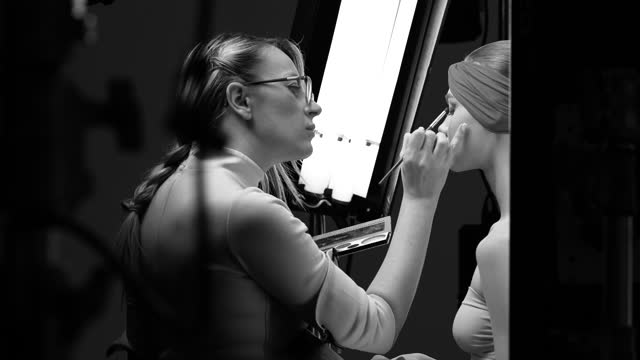Backstage make-up artist draws make-up for a girl.