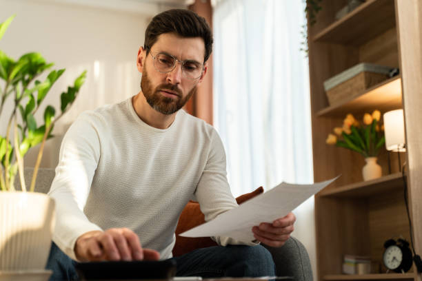istock Serious man wearing glasses holding paper, checking documents. Focused businessman 1472829547