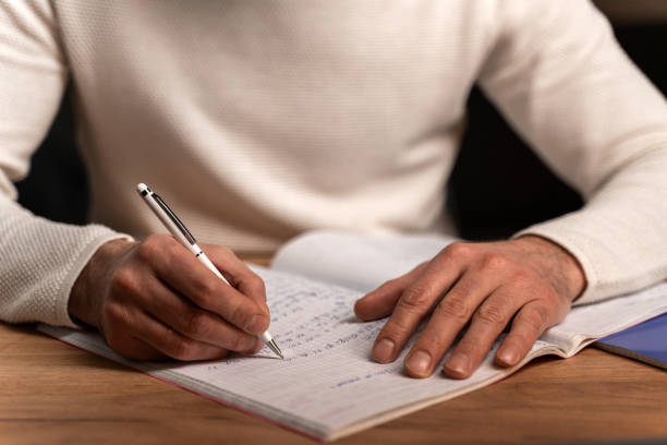 istock Handsome bearded man wearing white sweater writing letter at home during cozy evening 1472830255