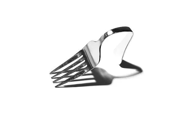 Silver Fork bent backwards over a white background.