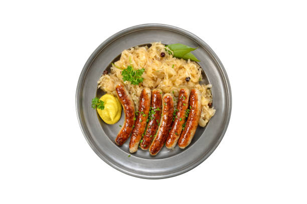 Fried Nuremberg sausages with sauerkraut served on a pewter plate isolated on white background