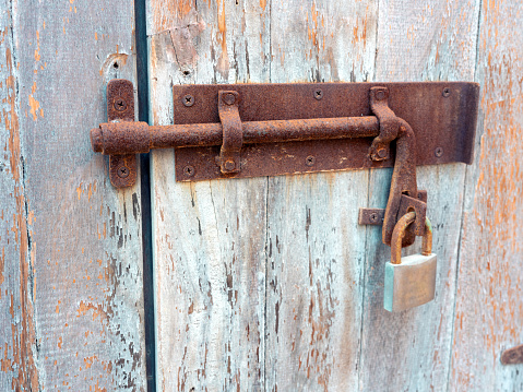 Rusty bolt with padlock on an old door