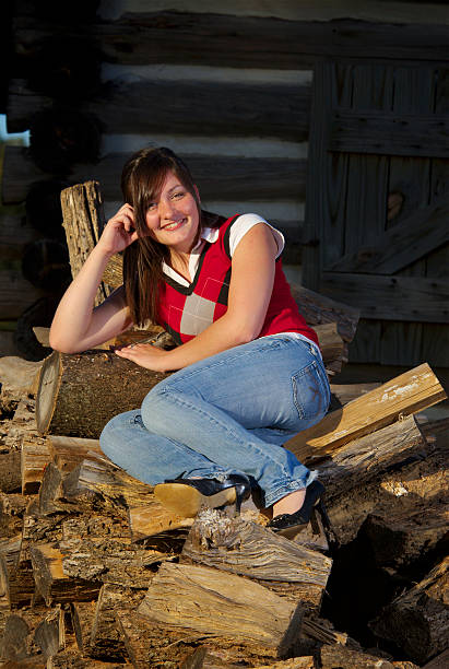 Teenager on firewood outside cabin stock photo