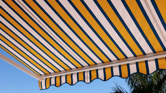 striped retractable awning opens against blue sky