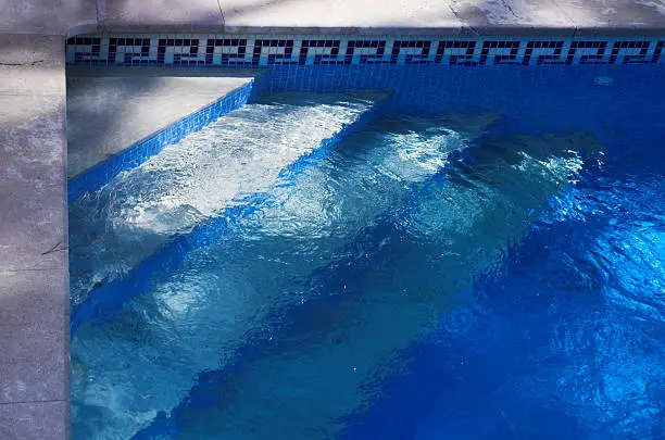Swimming pool steps, down into the cool blue water
