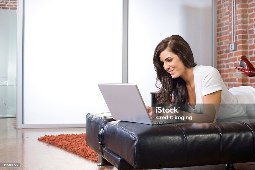 Jeune femme sur un ordinateur portable dans un loft moderne ou la maison - Photo de Adolescent libre de droits