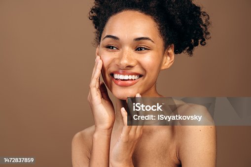 istock Face skin care. Woman applying cosmetic cream on clean hydrated skin portrait. Beautiful happy smiling multiracial girl model with natural makeup applying facial moisturizer. Beauty product concept 1472837859