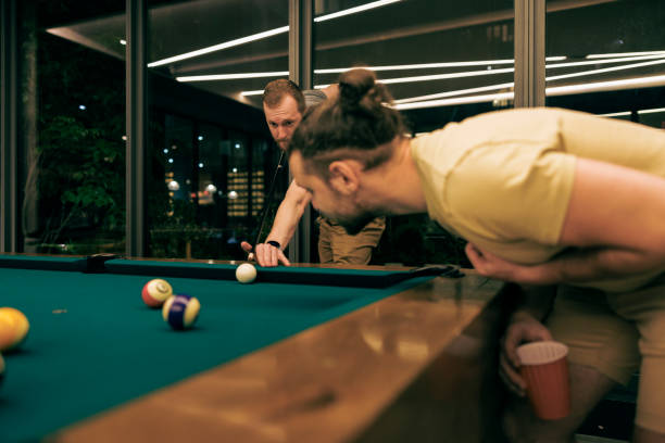 A pair of friends playing pool game together.