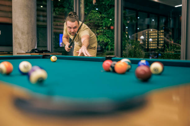 Playing Russian billiards on a green table. A white ball falls into the corner pocket. Top view. A successful shot close up. Pastime at home playing sport game hobby.