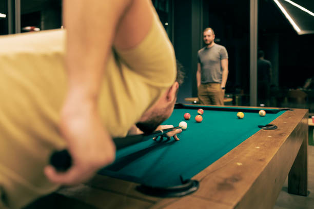 istock Concentrated friends playing snooker in a pool hall. 1472839664