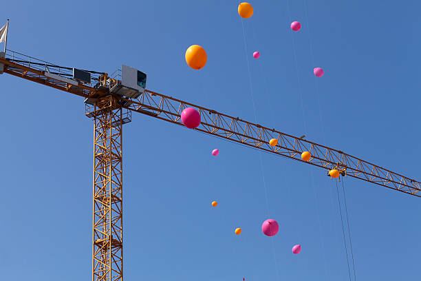 Multicolored balloons flying across a construction crane.