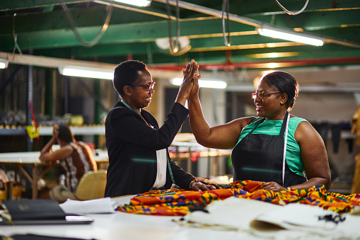 african business woman of textile factory wearing a black jacket with a white blouse giving employee high 5