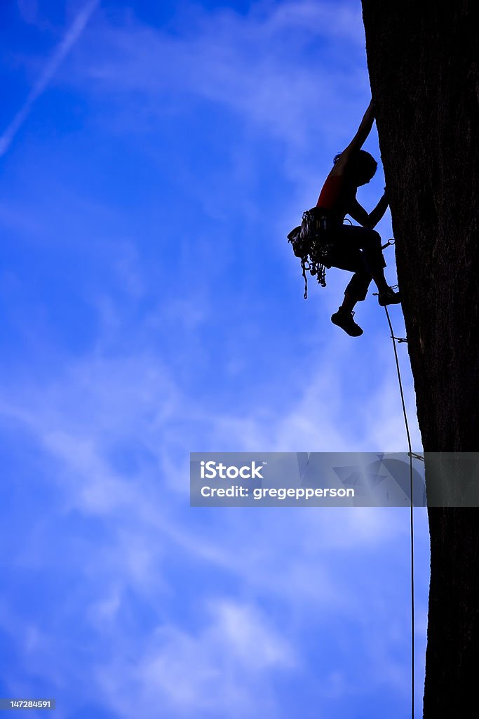 Rock climber clinging to a cliff. A climber is silhouetted as she clings to a steep rock face in Joshua Tree National Park, California. Challenge Stock Photo