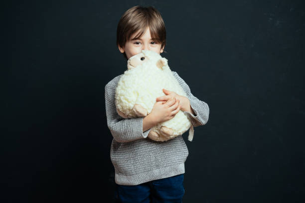 istock Little boy hugs his plush toy lamb 1472847152