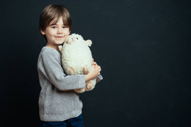 Little boy hugs his plush toy lamb