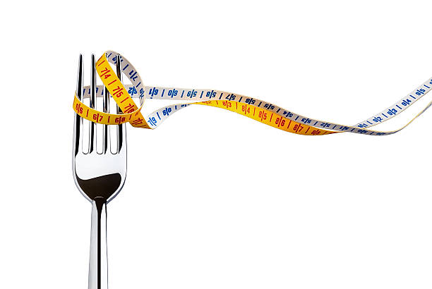 Diet concept represented with a fork and measuring tape stock photo