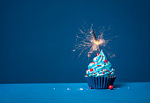 青の背景に青のカップケーキと赤と白の振りかけと点灯線香花火。