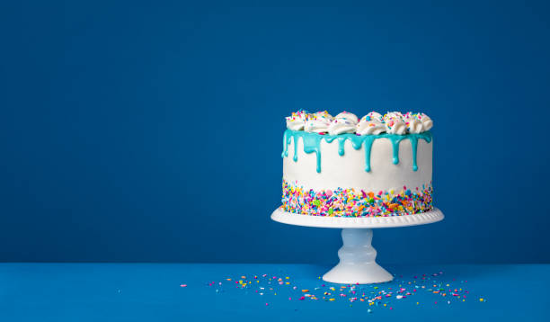 濃い青の背景に白い誕生日のドリップケーキとティールガナッシュ