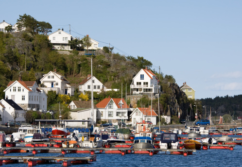 Small coastal town and local harbor in southern Norway, near Lyngoer. Typical for the area, houses are built hillside and near each other.